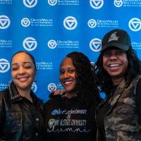 Three women posing for photo in front of GV back drop